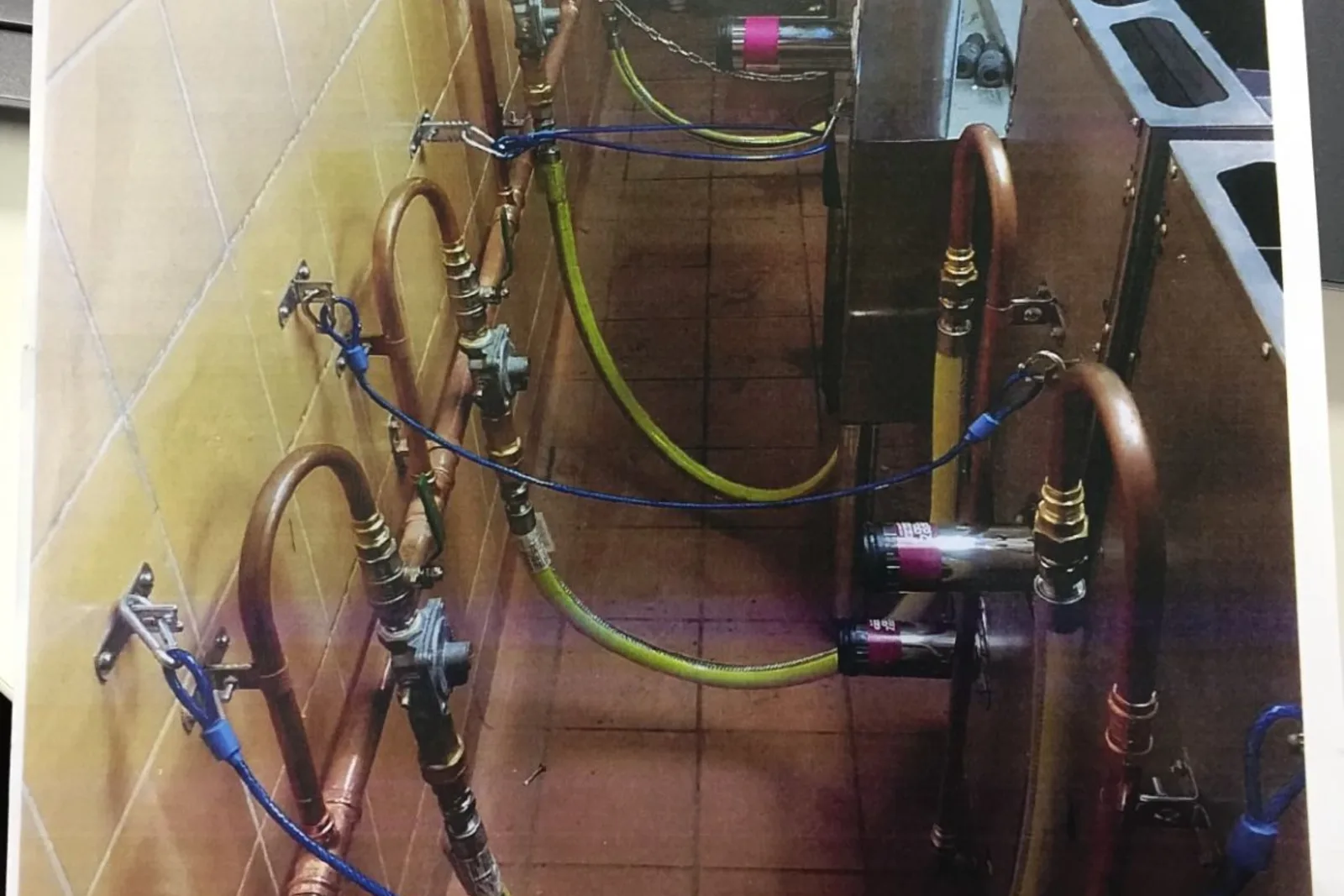 Gas appliances connected with copper lines and gas hoses in a commercial kitchen