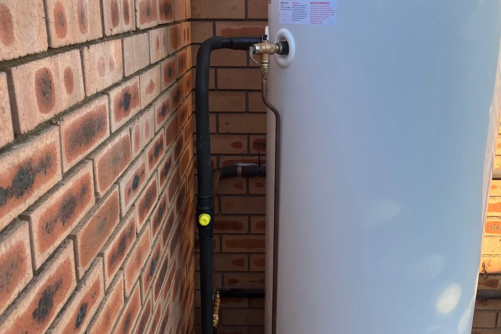 Hot water system installed against a brick wall