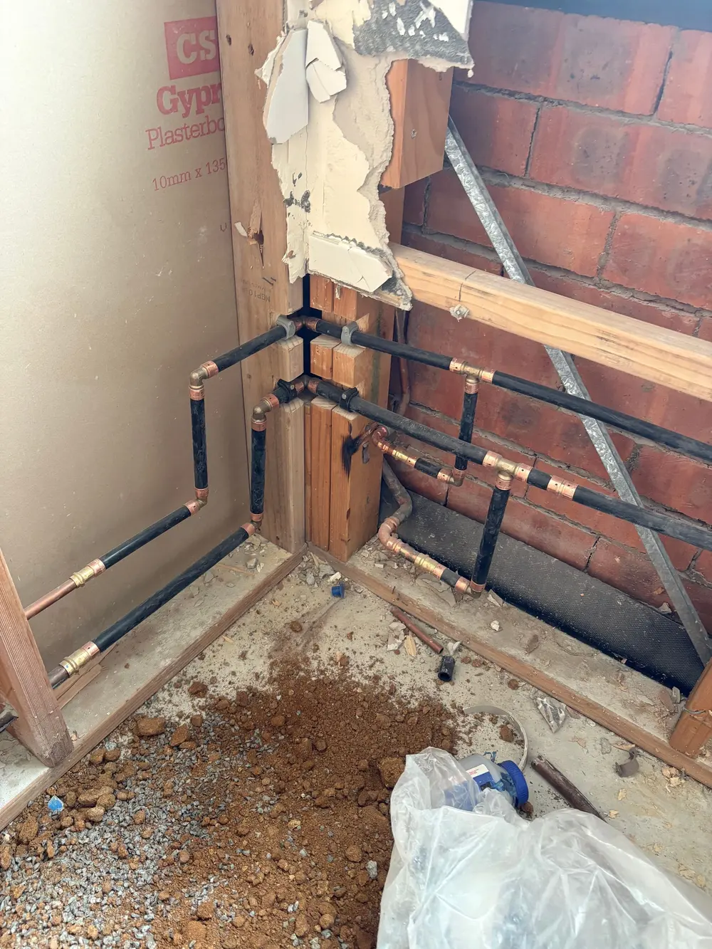Copper and plastic plumbing pipework installed inside an opened wall